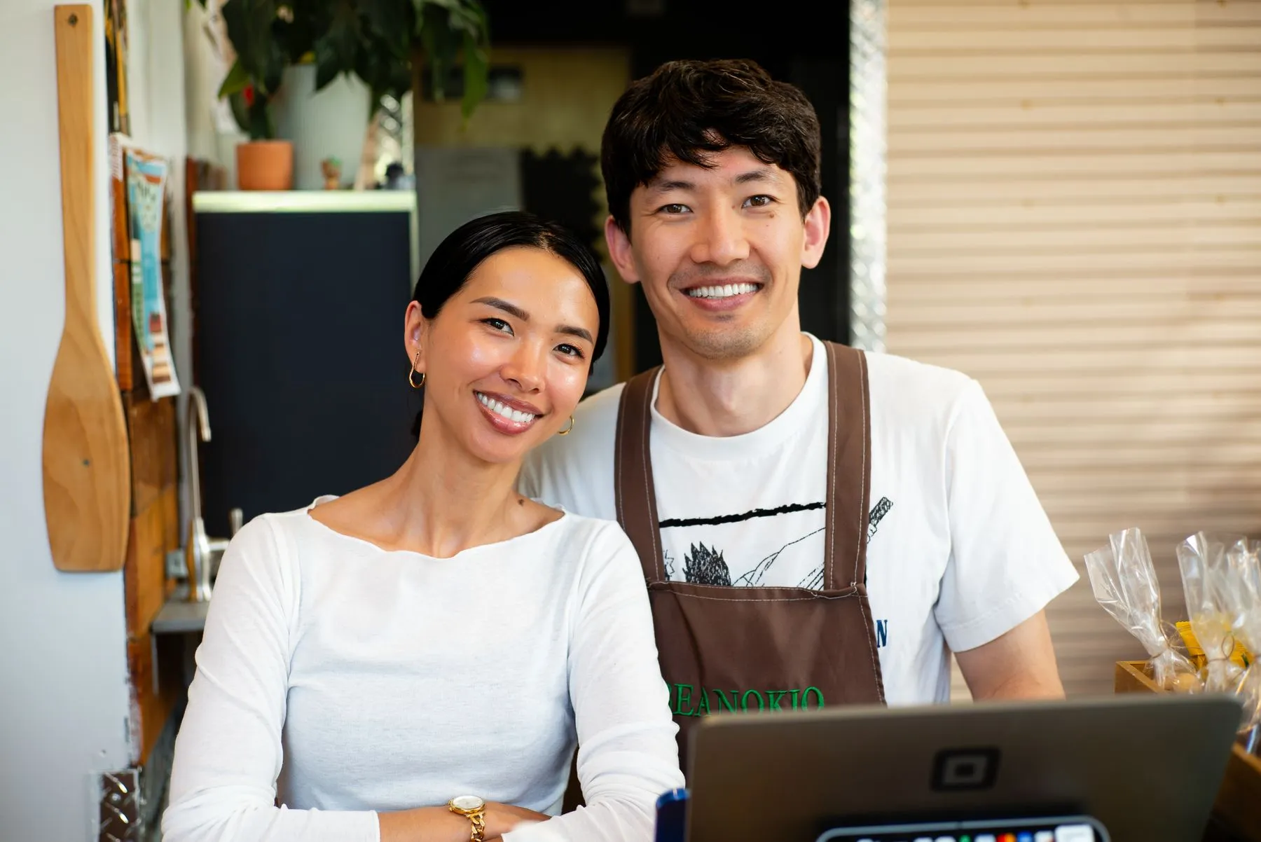 Two cafe owners smiling together behind their counter